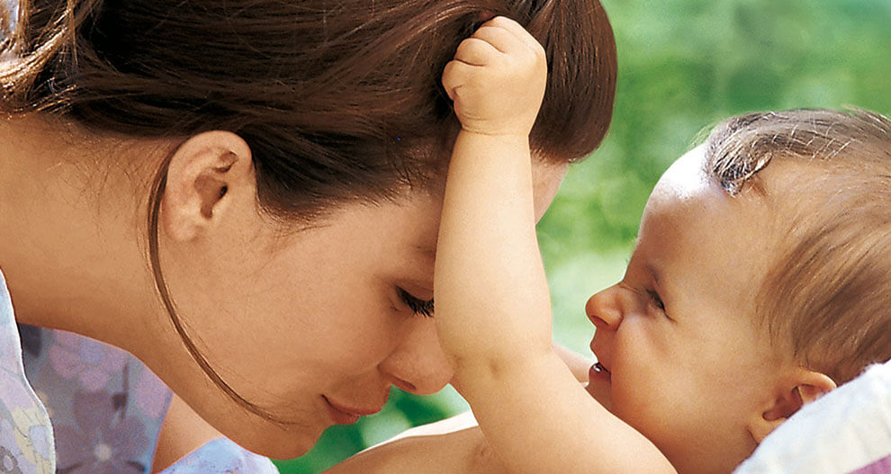 A woman and a baby share a moment of connection outdoors.