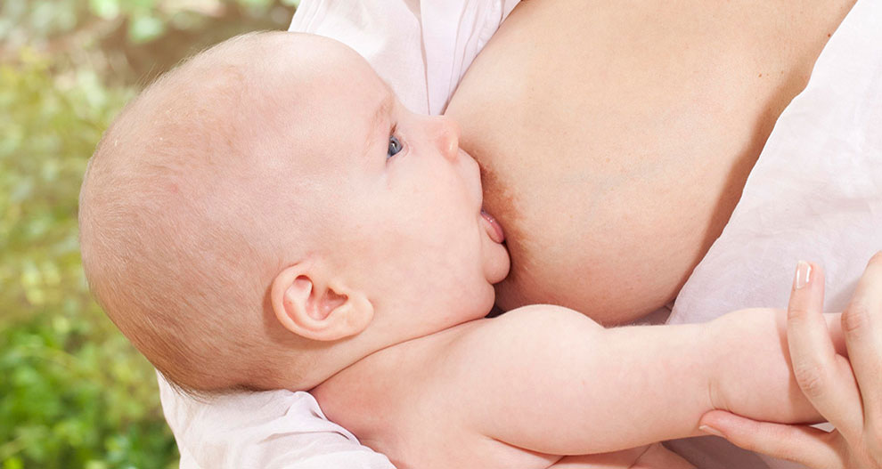 A baby is nursing from a woman.
