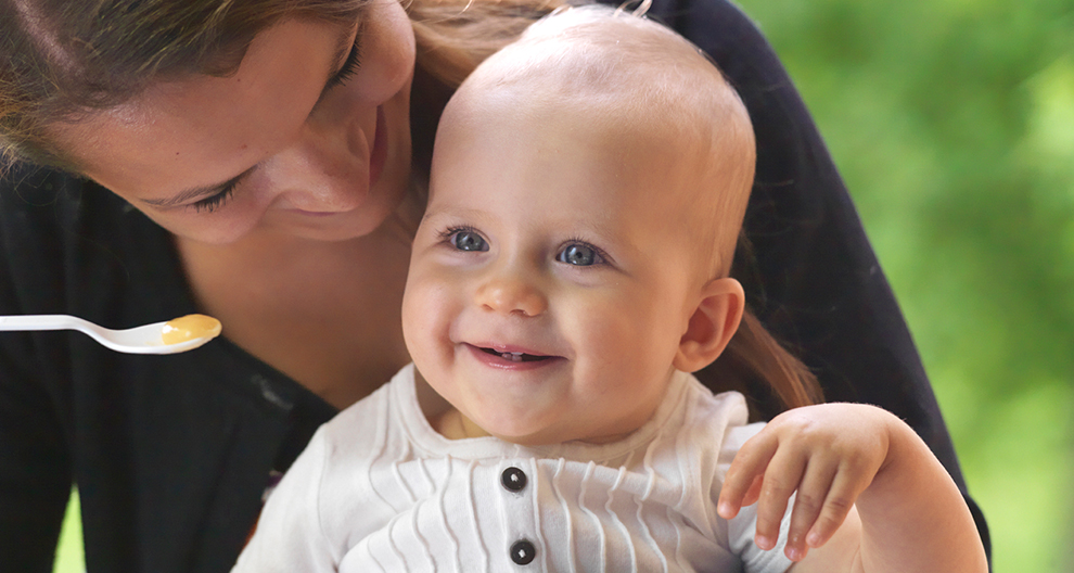 A woman feeds a baby with a spoon.